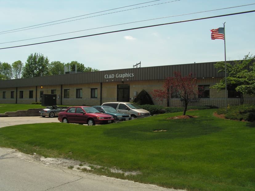 "Офис компании CL&D Graphics в Окономивоке, штат Висконсин, с американским флагом и парковкой перед зданием"